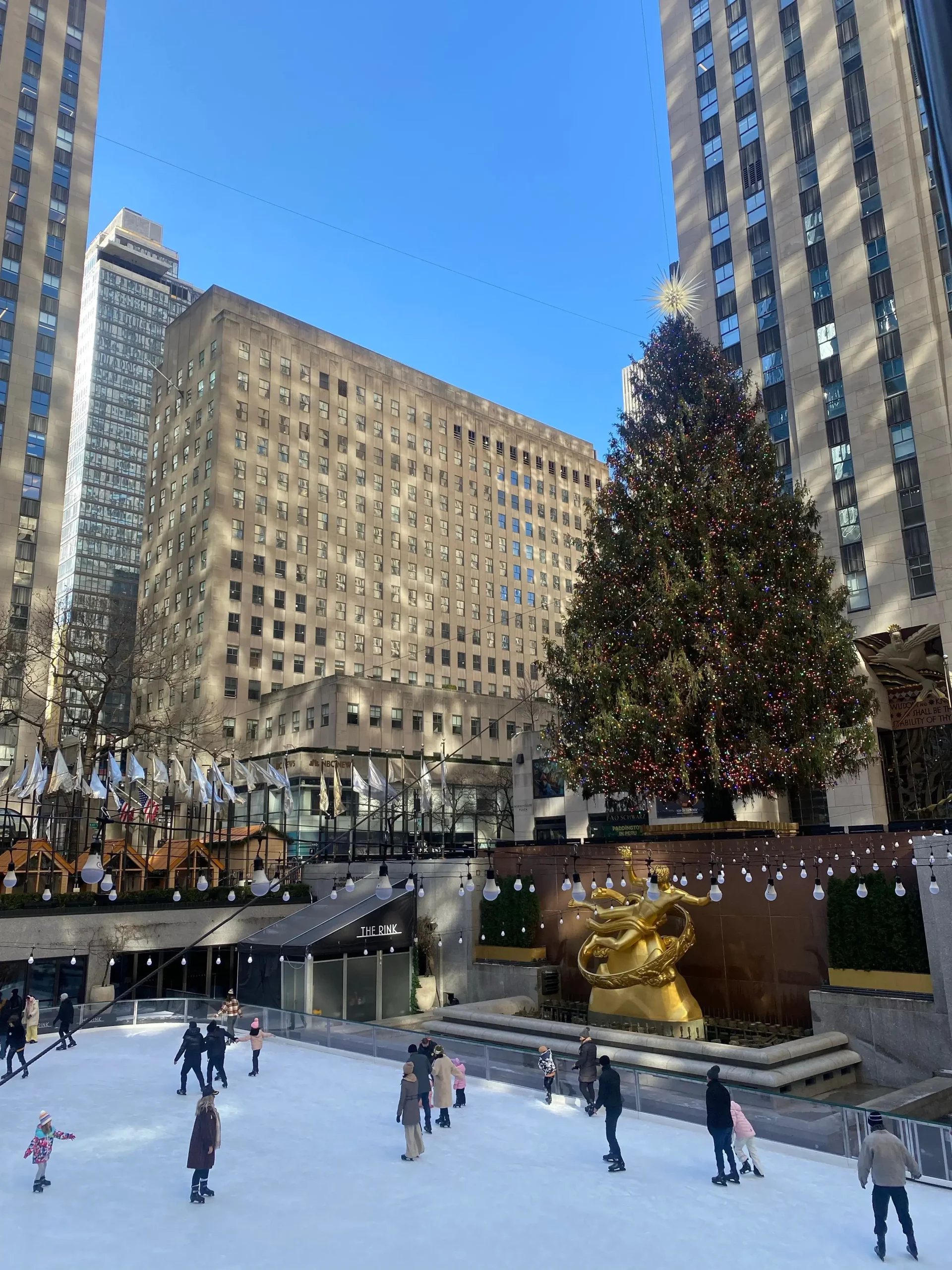 Un grand sapin de Noël illuminé et une patinoire extérieure à New York avec des patineurs