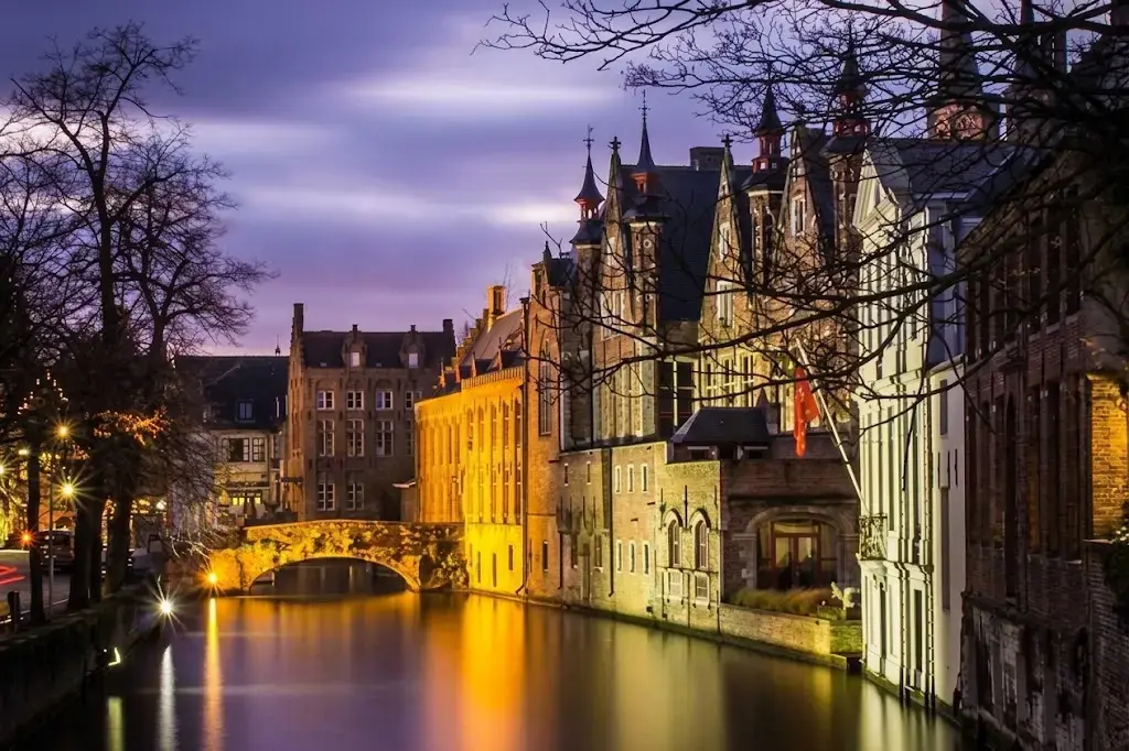 Quai illuminé de Bruges avec ses bâtiments historiques reflétés la nuit