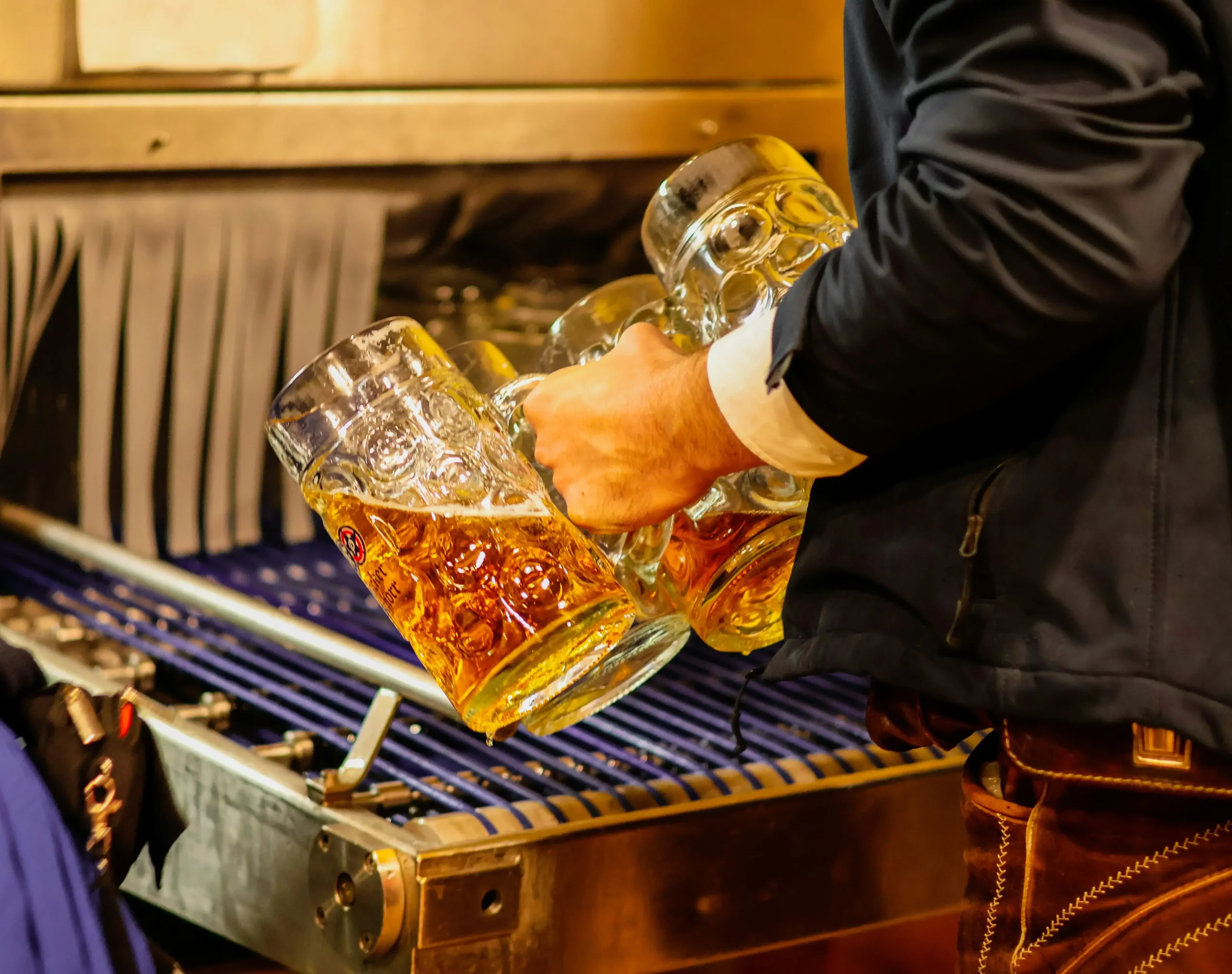 Gros plan d'un homme portant plusieurs grandes chopes de biere a Oktoberfest