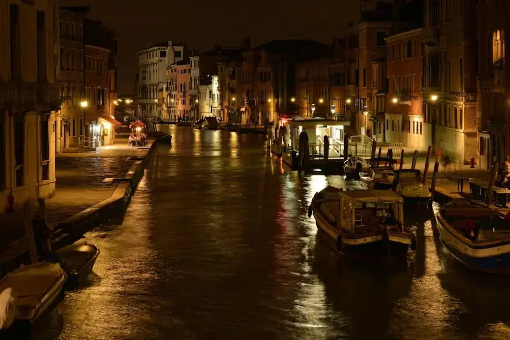 Canal à Venise la nuit illuminé par les lampadaires avec reflets dans leau
