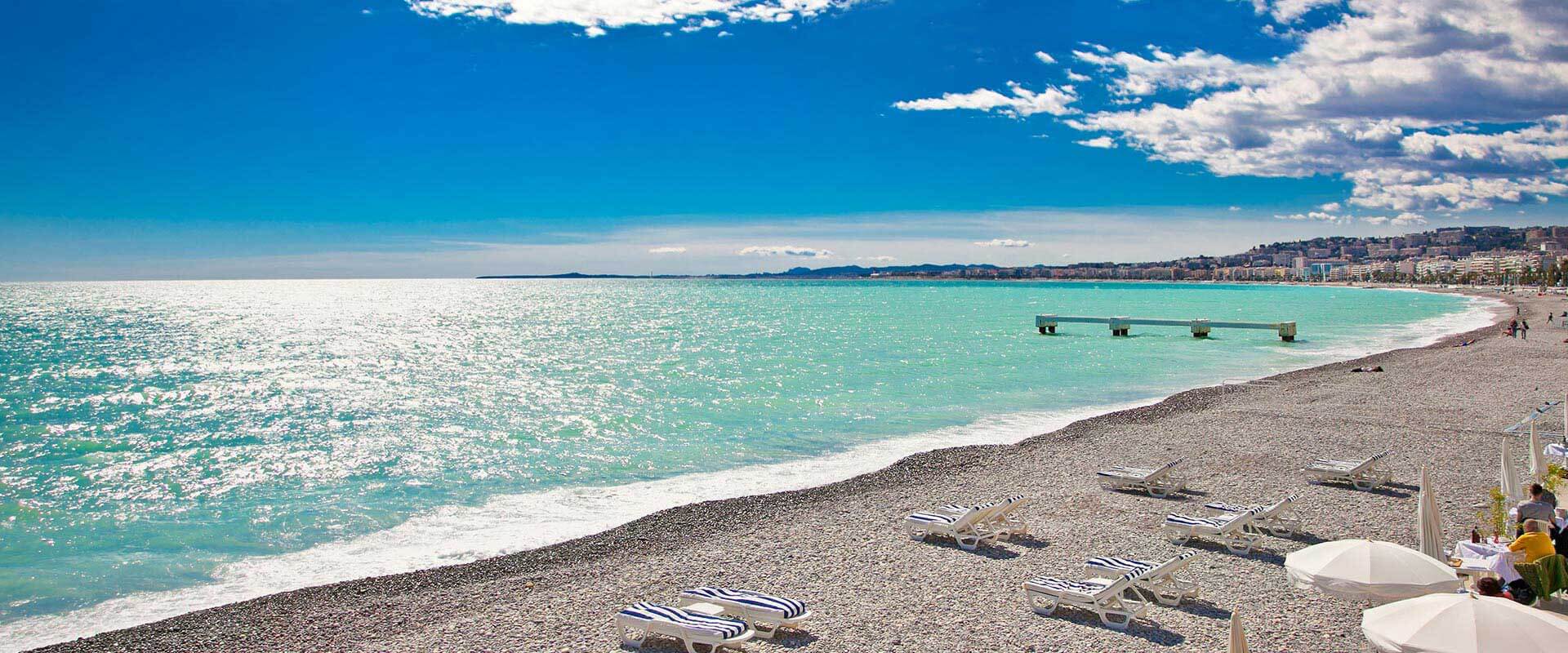 Vue sur la plage de Nice avec la mer bleue et un ciel dégagé avec des nuages ​​sur l'arène