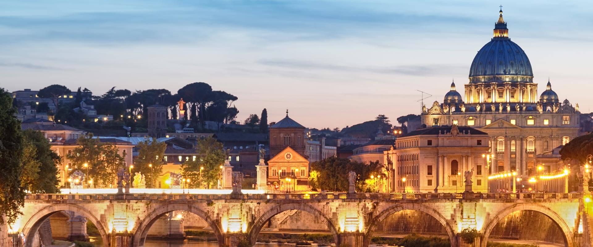 Vue nocturne de la basilique Saint-Pierre de l'autre côté du pont illuminé sur le Tibre à Rome.